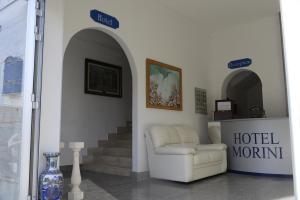 una habitación de hotel con una silla blanca y un jarrón en Hotel Morini, en San Foca