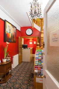 a room with a clock on a red wall at Gatwick Turret Guest House in Horley