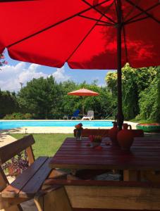 a picnic table with a red umbrella next to a pool at Villa Alkyon - Dreamy 3BR, Pool & BBQ next to Varnavas Beach in Grammatiko