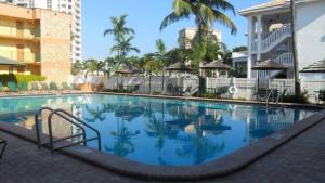 a swimming pool at a resort with palm trees at Surf Rider Resort in Pompano Beach