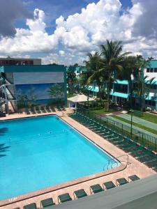a large swimming pool with chairs and a building at Surf Rider Resort in Pompano Beach