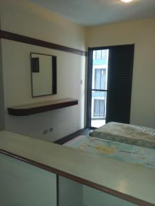 um quarto com uma cama, um espelho e uma janela em Flat - Palladium Apart Service em São Vicente