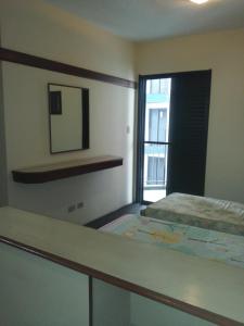 a bedroom with a bed and a mirror and a window at Flat - Palladium Apart Service in São Vicente +7 photos