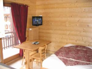 Habitación de madera con mesa y TV en la pared en Studio Danay, en Le Grand-Bornand