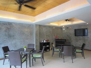 a dining room with tables and chairs and a flat screen tv at White Cat Hotel in Khao Lak