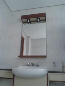 uma casa de banho com um lavatório branco e um espelho. em Flat - Palladium Apart Service em São Vicente
