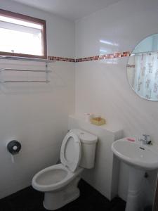 a white bathroom with a toilet and a sink at White Cat Hotel in Khao Lak