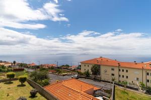 - une vue sur une ville avec des toits d'orange et un ciel nuageux dans l'établissement Caniço V by An Island Apart, à Caniço