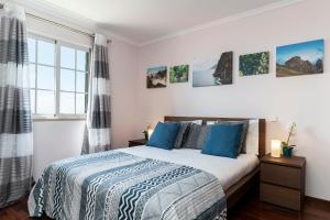 - une chambre avec un lit et des oreillers bleus dans l'établissement Caniço V by An Island Apart, à Caniço