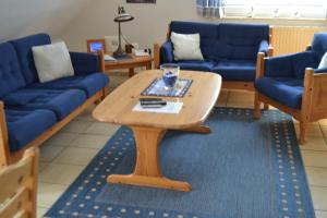 a living room with a coffee table and blue couches at Haus Schimmelreiter in Greetsiel
