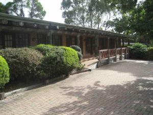 a building with a fence and some bushes and trees at Mahogany Park in Cranbourne