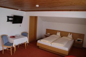 a bedroom with a bed and a table and a tv at Der Oswalderhof in Obertilliach