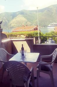 a table and chairs on a balcony with a bottle of wine at Room With Sea View in Kotor