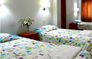 una habitación de hotel con 2 camas y un jarrón con flores en Hostal Residencial Lino, en Huaraz