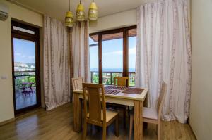 a dining room with a table and chairs and windows at Apartment Balchik in Balchik