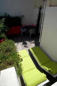 patio z zielonymi poduszkami, stołem i ławką w obiekcie Villa des Canuts w mieście Lyon