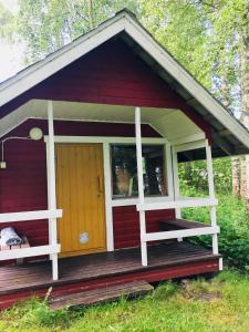a red cottage with a porch and a door at Ollila Rantamökit in Kerimäki