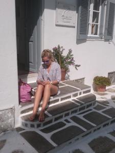 a young girl sitting on a ledge looking out a window at Galini Hotel in Mikonos