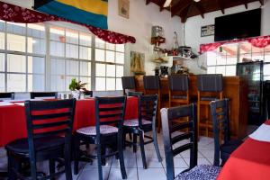 a restaurant with black chairs and a red table at Nathan's Lodge in Kemps Bay