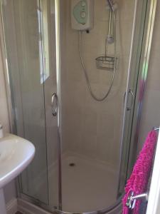 a shower with a glass door next to a sink at Eden Cottage in Haltwhistle