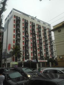 um edifício alto com carros estacionados em frente em Flat - Palladium Apart Service em São Vicente