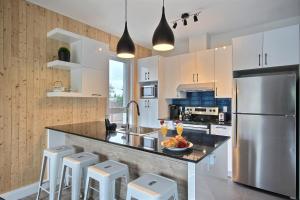 uma cozinha com um frigorífico de aço inoxidável e armários brancos em The City Life em Cidade de Quebec