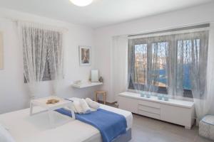 a white bedroom with a bed and a window at Villa Lina Syros in Azolimnos Syros +69 photos