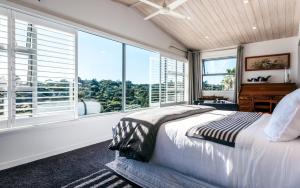 a bedroom with a bed and windows and a piano at Wild Thyme in Oneroa