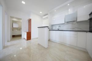 biała kuchnia z białymi szafkami i zlewem w obiekcie Apartmani Postimana w mieście Pašman