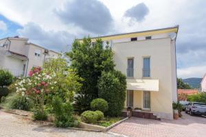 Un bâtiment blanc avec beaucoup de plantes et de fleurs dans l'établissement apartmani Ivana, à Kaštela