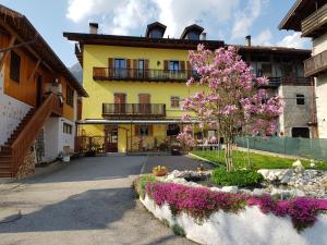 un bâtiment jaune avec un arbre aux fleurs roses dans l'établissement Albergo Casavecchia, à Tiarno di Sopra