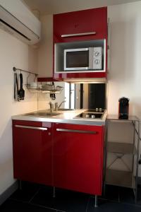 a kitchen with red cabinets and a microwave at Villa des Canuts in Lyon