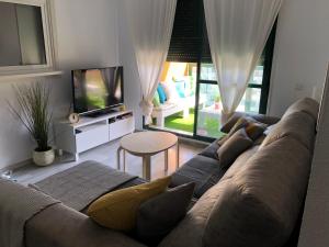 sala de estar con sofá y TV en Luxury Apartment Bajondillo Beachfront, en Torremolinos