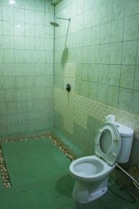 a bathroom with a toilet and a shower at Putu Guest House in Canggu