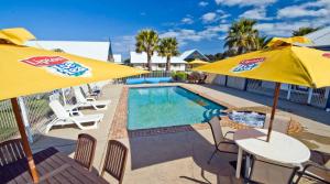 een zwembad met twee gele parasols en stoelen naast een zwembad bij Torquay Tropicana Motel in Torquay