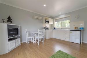 a kitchen with white cabinets and a table with chairs at Tokemata Retreat in Cobram