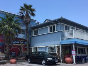 een auto geparkeerd voor een huis met palmbomen bij The Shores Inn in Ventura