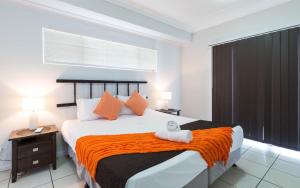 a bedroom with a large bed with an orange blanket at Cairns City Apartments in Cairns