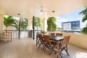 a balcony with a table and chairs and palm trees at Cairns City Apartments in Cairns