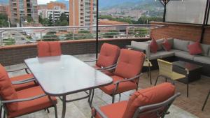 balcón con mesa, sillas y sofá en The 9's Apartahotel, en Medellín