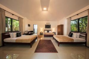 a bedroom with two beds in a room with windows at Cabilao Sanctuary Beach & Dive Resort in Loon