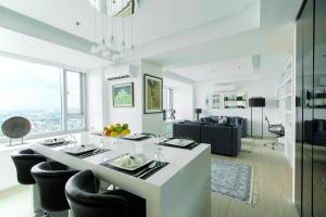a white living room with a table and chairs at The Alpha Suites in Manila