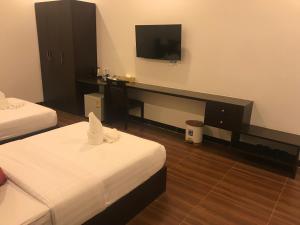 a hotel room with two beds and a desk with a television at Apple Hotel Two - Near Phnom Penh Airport in Phnom Penh