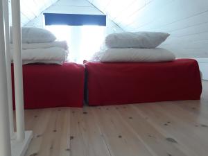 - deux oreillers installés au-dessus de deux ottomanes rouges dans une chambre dans l'établissement Göta kanal Hajstorp, à Töreboda