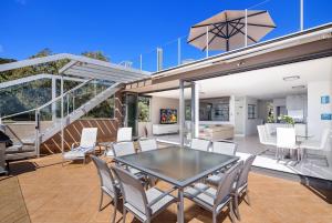 a dining area with chairs, tables, and tables with umbrellas at Picture Point Terraces in Noosa Heads