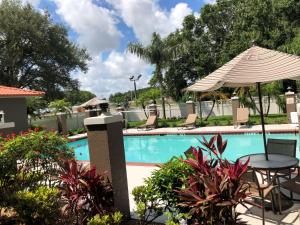 a swimming pool with a table and an umbrella at Best Western Plus Bradenton Hotel & Suites in Bradenton
