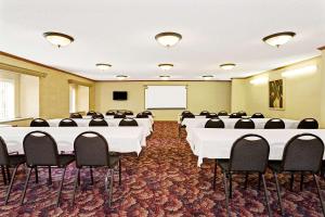 une salle de conférence avec des tables blanches et des chaises noires dans l'établissement Microtel Inn & Suites by Wyndham Florence/Cincinnati Airpo, à Florence