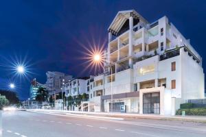 a white building on the side of a street at night at Cairns City Apartments in Cairns