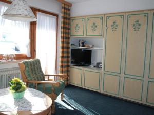a living room with a table and a television at Ferienapartmenthaus Hubertushof in Mittenwald