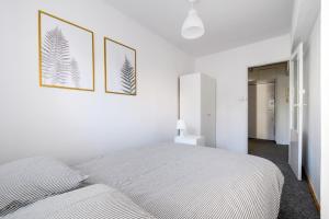 ワルシャワにあるChmielna Hammock Apartmentの白いベッドルーム(ベッド1台、フレーム写真2枚付)